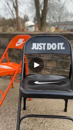 an orange and black chair sitting on top of a sidewalk next to a brick wall