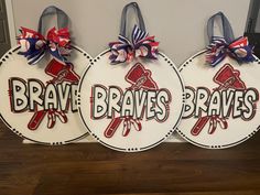 three wooden signs with red, white and blue bows hang from hooks on a wall