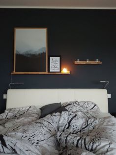 the bed is made and has two framed pictures on the wall above it, along with candles