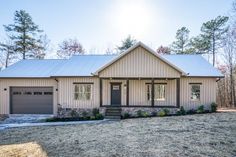 a house in the woods with a metal roof and two garages on each side