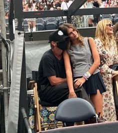 a man and woman sitting on top of a chair next to each other at a tennis match