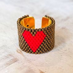 a close up of a bracelet with a red heart on the front and black dots on the back