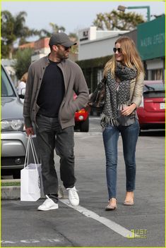 a man and woman walking down the street with shopping bags in hand, holding hands