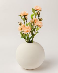 a white vase filled with pink flowers on top of a table