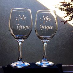 two wine glasses sitting side by side on a window sill with the words mr and mrs geiger written on them