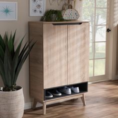 a wooden cabinet sitting next to a potted plant in front of a window on top of a hard wood floor