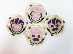 four purple and green flower buttons on a white surface