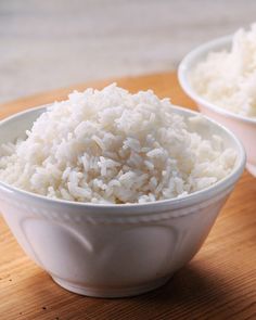 white rice in a green bowl with chopsticks next to it on a table