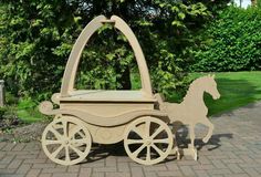 a wooden horse drawn carriage sitting on top of a brick walkway next to trees and bushes