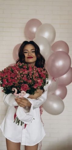 a woman holding flowers and balloons in her hands