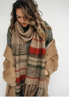 a woman with long hair wearing a scarf and standing in front of a white background