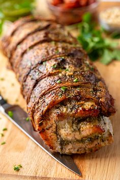 a meatloaf is cut into pieces on a wooden cutting board with a knife