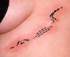 a woman's stomach with an arrow tattoo on her left side ribcage