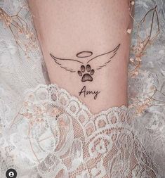 a woman's leg with a dog paw and an angel wing tattoo on it