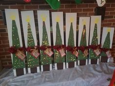 several christmas trees are on display in front of a brick wall and decorated with red ribbon