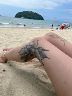 a woman's legs with tattoos on the beach