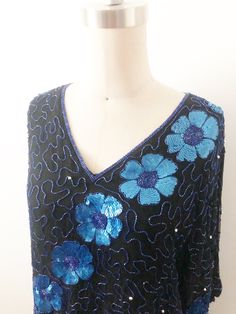 This is a beaded silk top. The random design is done with iridescent cobalt blue bugle beads. The large flowers are made up of the same beads with the petals done in sequins. There are also round silver beads interspersed front and back. My favorite part of this top is the scalloped effect the flowers give to the sleeves and hemline. A unique touch. No size tag, fits like a M/L with no stretch. Check measurements carefully. Lined with rayon. Length 26 inches Underarm to underarm 40 inches Waist Poodle Skirt, Blouse Silk, Beaded Blouse, Beaded Evening Bags, Bugle Beads, Beaded Top, Vintage Lingerie, Sequin Top, Large Flowers