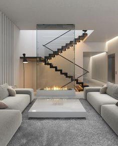 a modern living room with white furniture and a fire place in the center, along with stairs leading up to the second floor