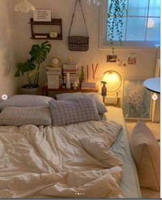 an unmade bed with pillows and blankets on it in a bedroom next to a window