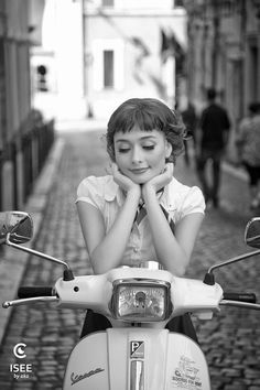 a woman sitting on top of a scooter with her hands under her chin