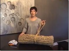 a woman standing next to a large bag on top of a wooden table in front of a painting