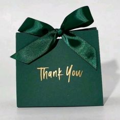 a green gift box with a bow and thank you written on the front in gold foil