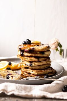 a stack of pancakes with blueberries and syrup being drizzled over them