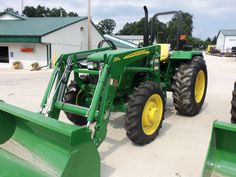 a green tractor parked in front of a building