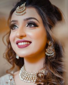 a woman in a bridal outfit smiling and wearing pearls on her necklace, earrings and choker