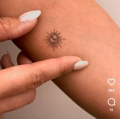 a woman's arm with a small sun tattoo on the left side of her arm