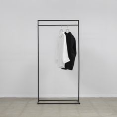 an iron clothes rack with two shirts hanging on it and one white shirt in the middle