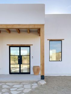 a white building with two large doors and a stone walkway leading to the front door