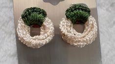 pair of earrings with green and white yarn wrapped around them