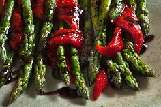 asparagus and red peppers on a plate with ketchup drizzled over them