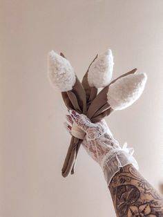 a person's hand holding a bunch of flowers with white gloves on their arm