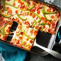 a pizza with pepperoni and jalapenos is being cut into squares by a spatula