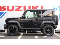 a black jeep parked in front of a suzuki sign