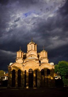 an old church with dark clouds in the background