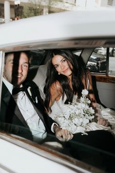 a bride and groom sitting in the back of a car