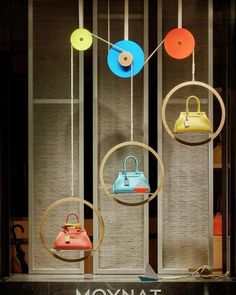 several different colored purses are hanging in front of a store window with the word moynat on it