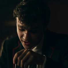 a young man in a suit is looking down at his bag while holding it with both hands