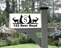 a sign that says 123 deer road in front of some trees and bushes with flowers