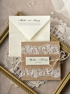 the wedding stationery is laid out on top of lace and burluck paper