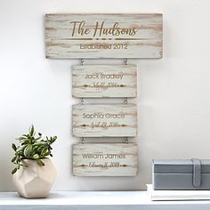 three wooden signs hanging on the side of a white wall next to a potted plant