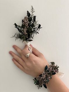 a person's hand with two bracelets on it and flowers attached to the wrist