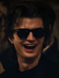 a man wearing sunglasses and smiling with his mouth open in front of the camera,