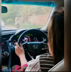 a woman driving a car while holding the steering wheel