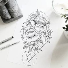 a drawing of flowers on paper next to a candle and some pencils with markers