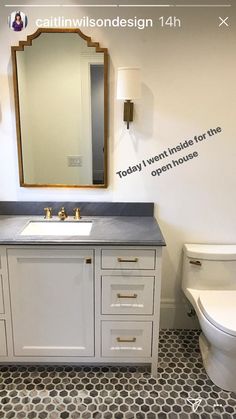 a white toilet sitting next to a bathroom sink under a mirror on top of a wall