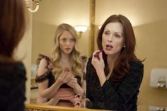 a woman brushing her teeth in front of a mirror with another woman looking at her